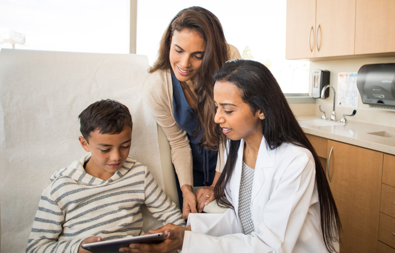 child looking at ipad with doctor